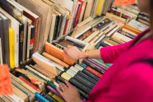 A person browsing through books on a shelf in a cozy bookstore.